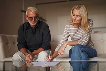 Two people signing divorce papers by consent.